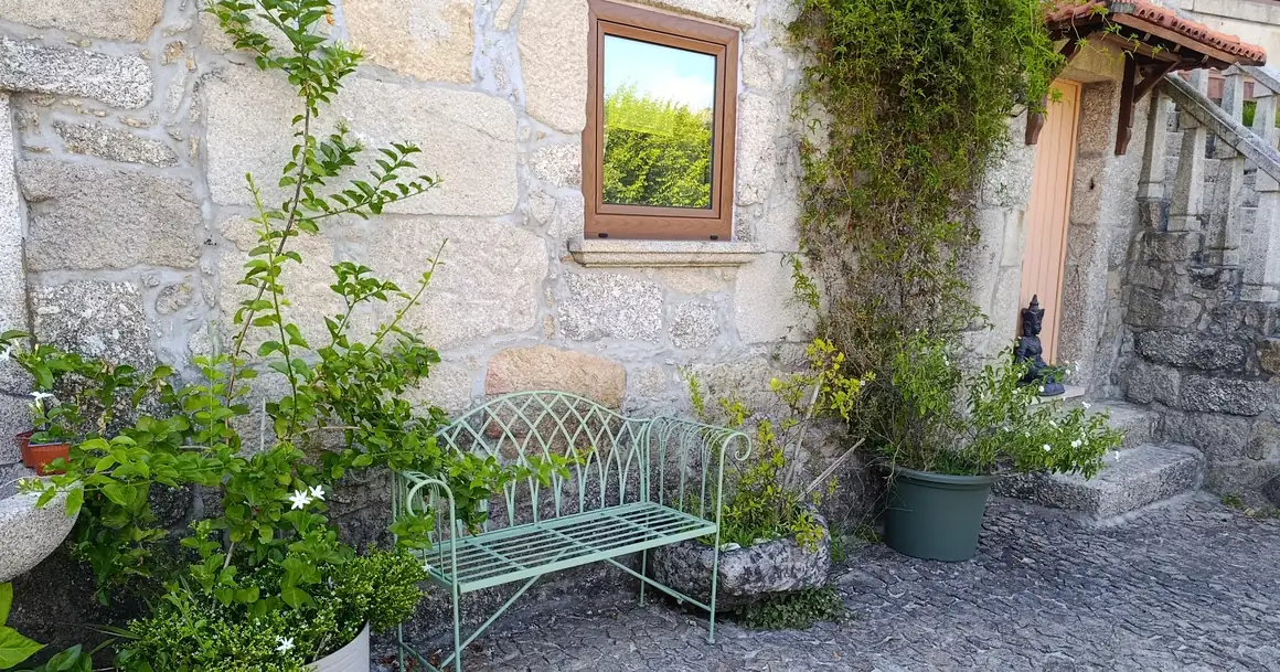 An iron bench against the granite wall, at the entrance to the quinta